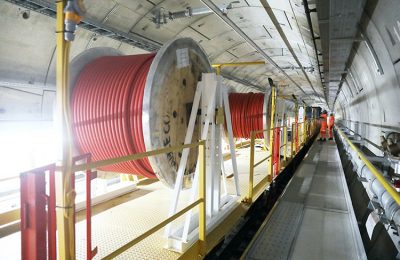 A construction train in a tunnel, carrying large reels of red cable